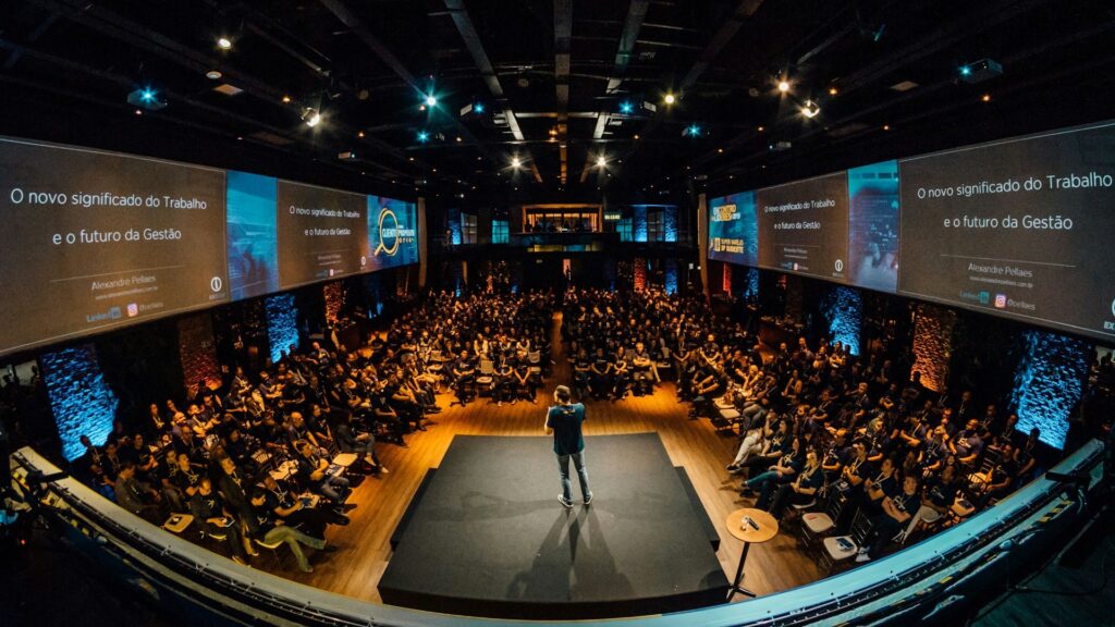 Spreker op podium tijdens conferentie met publiek, illustratie van personalisatie events