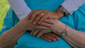 Handen van mantelzorger en oudere die steun tonen binnen mantelzorg dagelijks leven