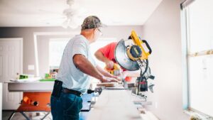 Man zaagt hout binnenshuis tijdens renovatie als onderdeel van onderhoudsbudget woning