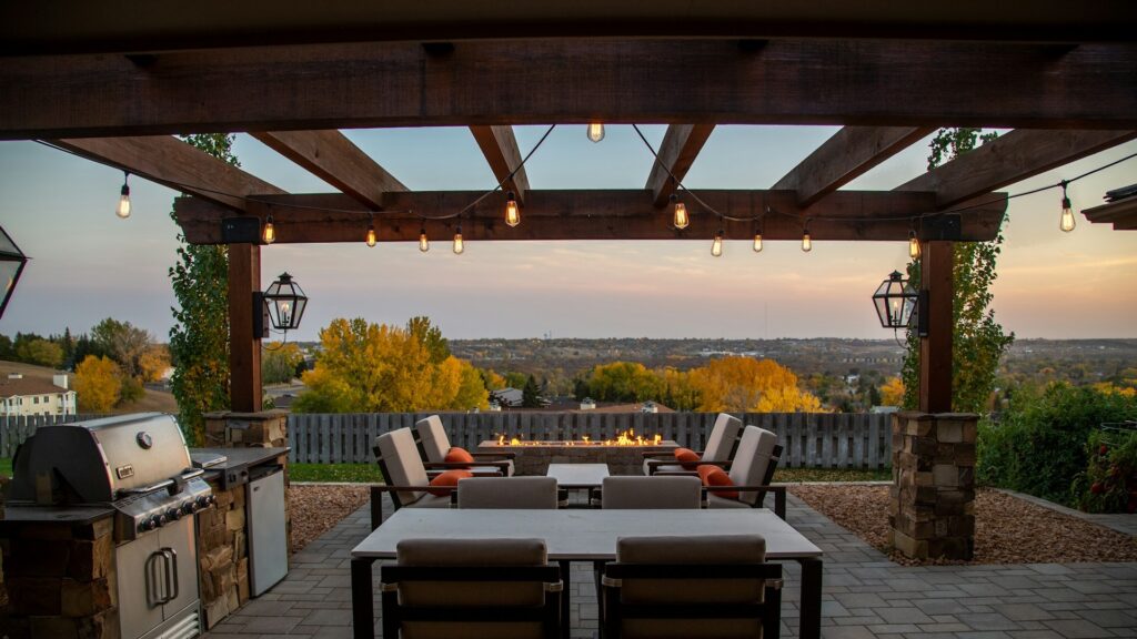 Buiten zitten comfortabel onder een houten terrasoverkapping met sfeerverlichting en loungehoek